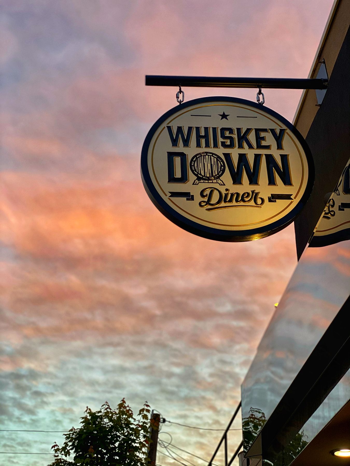 The hanging Whiskey Down Diner sign against a pink sunset sky