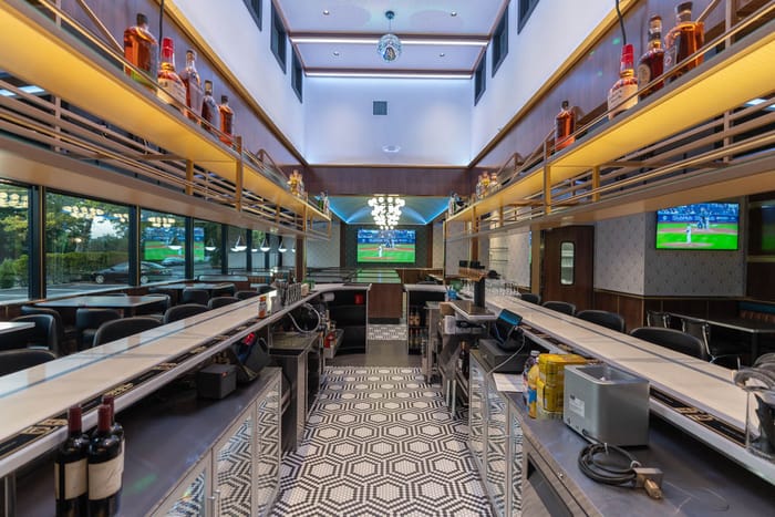 Behind the bar in Babylon Village, bottles on the overhead rails