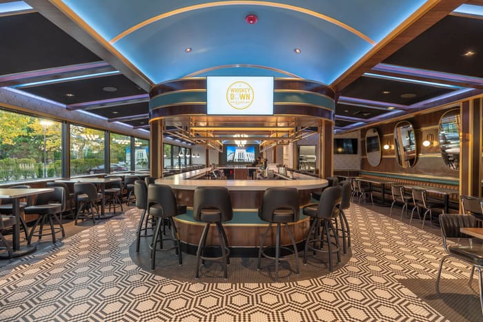 The curved center bar in Babylon Village, under a backlit ceiling
