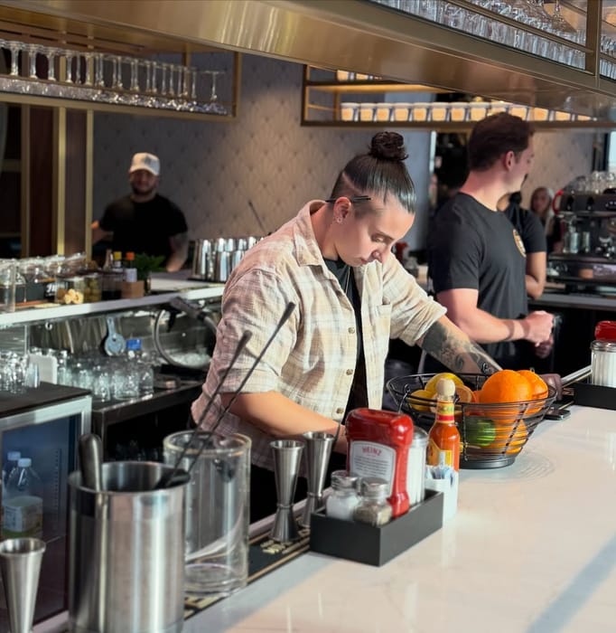 A bartender making drinks behind the Babylon Village bar