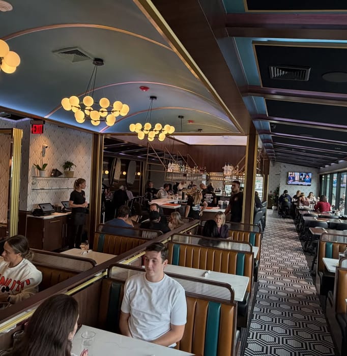 A full dining room in Babylon Village, booths and bar under the arched ceiling