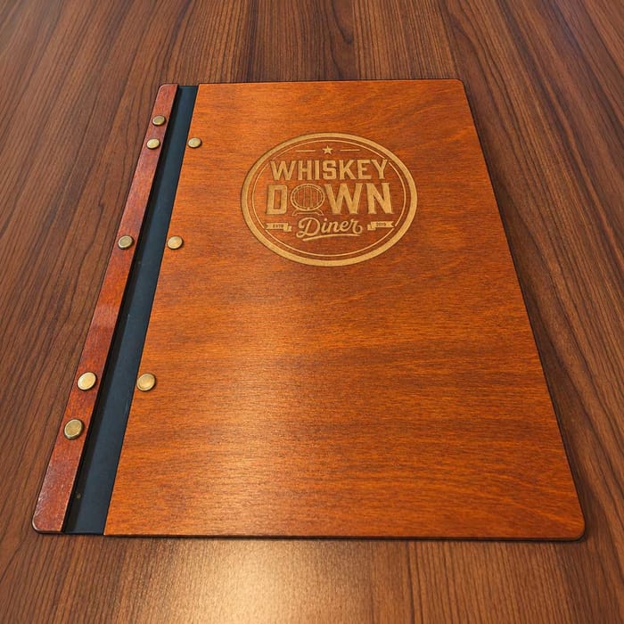 A wooden menu cover engraved with the Whiskey Down Diner logo