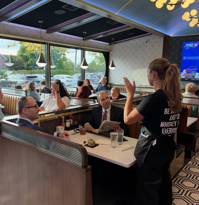 A server taking an order at a booth in Babylon Village